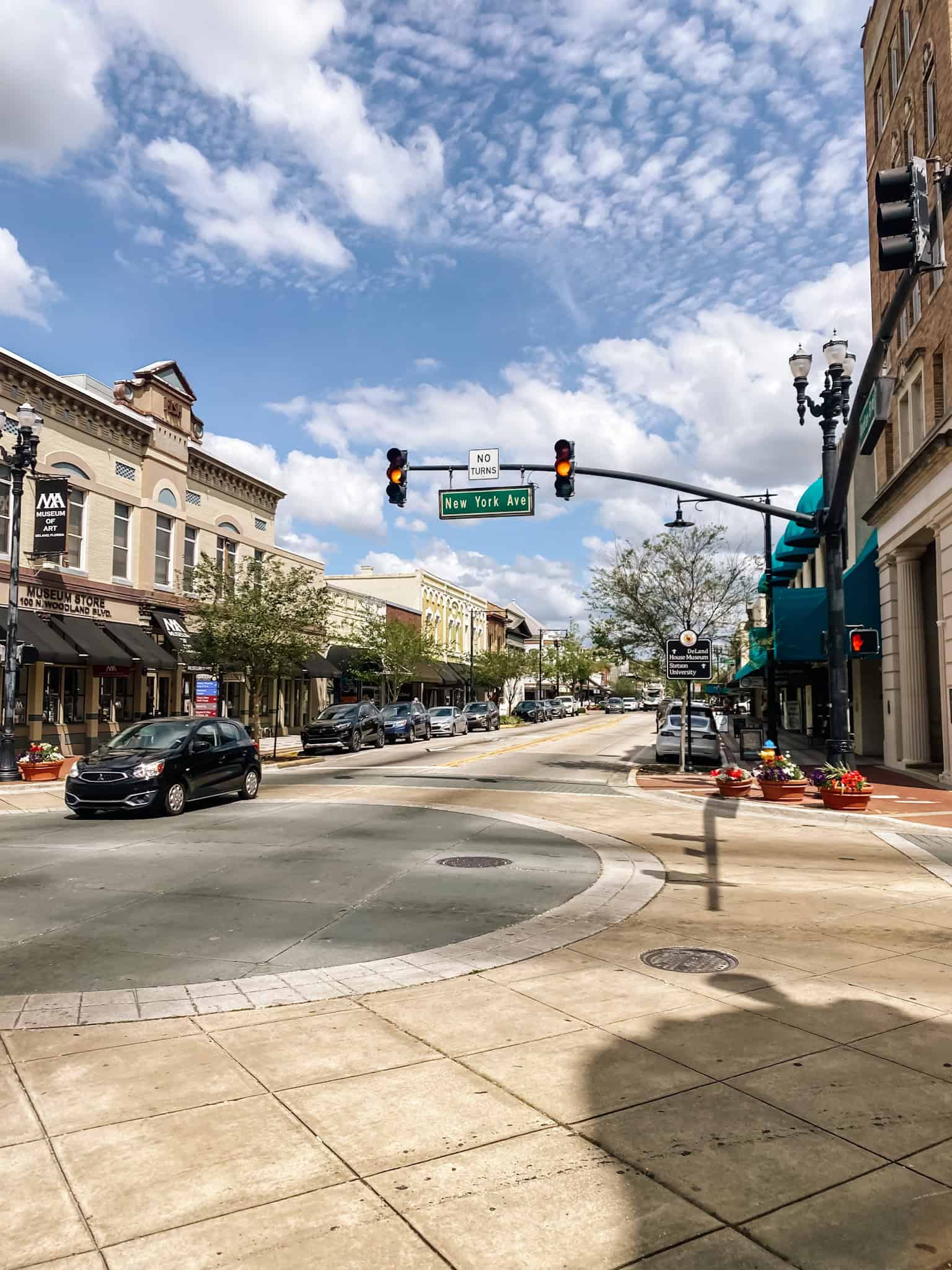 the main strip of downtown DeLand. Cars going through the stoplight with buildings on either side of the frame. Things to do in DeLand.